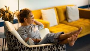 Eine Frau macht es sich auf einem Sessel gemütlich.