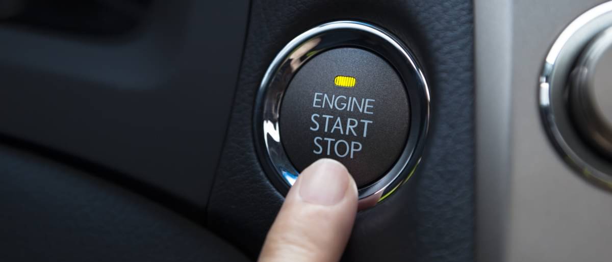 Ein Finger, der auf dem Start/Stopp Knopf eines Autos liegt - Auto anmelden Kosten