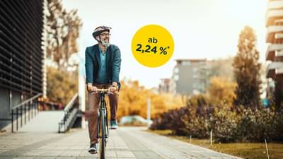 Mann im mittleren Alter, der mit dem Fahrrad durch die Stadt fährt: Ratenkredit ab 2,24% p.a.*