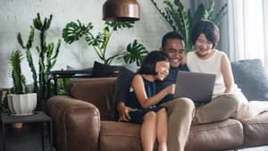 Familie sitzt auf Sofa und shoppt dank einer guten Bonität, sorglos im Internet