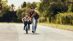 Ein Vater bringt seinem Sohn das Fahrradfahren bei und  gibt ihm Anschwung beim Starten.