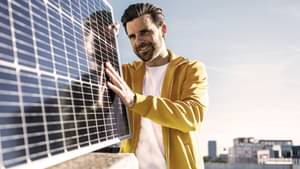 Ein Mann platziert auf seinem Dach einen Sonnenkollektor.