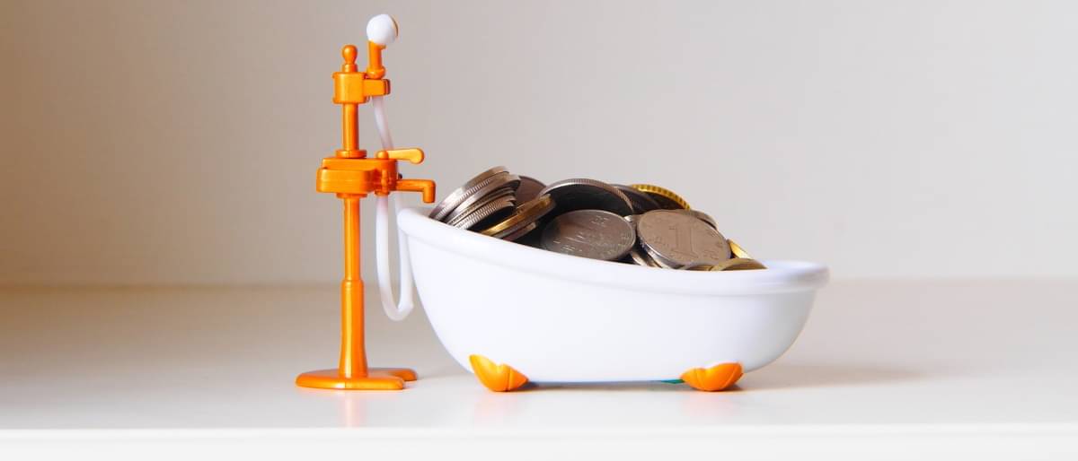 Eine kleine mit Münzen gefüllte Badewanne und einer orangenen Pumpe