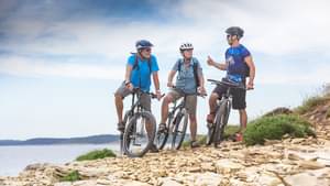 Drei Radfahrer halten am Meer an und unterhalten sich