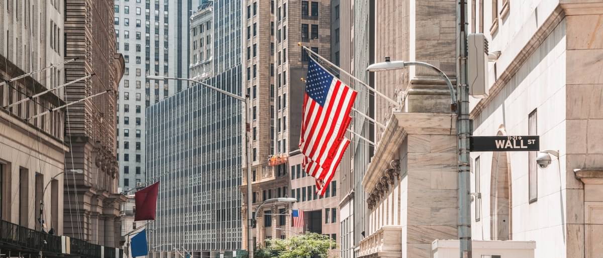 Blick auf die Hochhäuser der Wall Street und eine US-Flagge