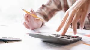 Ein Mann im karierten Hemd macht sich Notizen und tippt Zahlen in einen Taschenrechner.