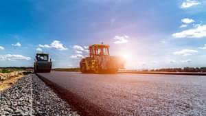 Zwei Arbeitsmaschinen auf einer frisch geteerten Straße