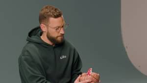 Dominik Kieu sitzt in einem Studio auf einem weißen Würfel.