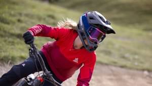 Mountain-Bikerin mit Schutzhelm fährt schnell über einen Parcours