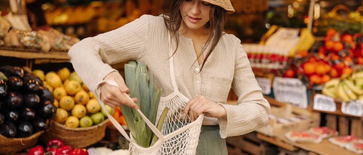 Eine junge Frau verstaut ihre Einkäufe in einer Netztasche