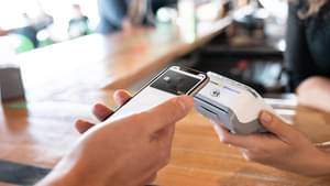 Ein Handy mit VISA-Karte auf dem Bildschirm wird an ein Kartenzahlungsterminal gehalten.