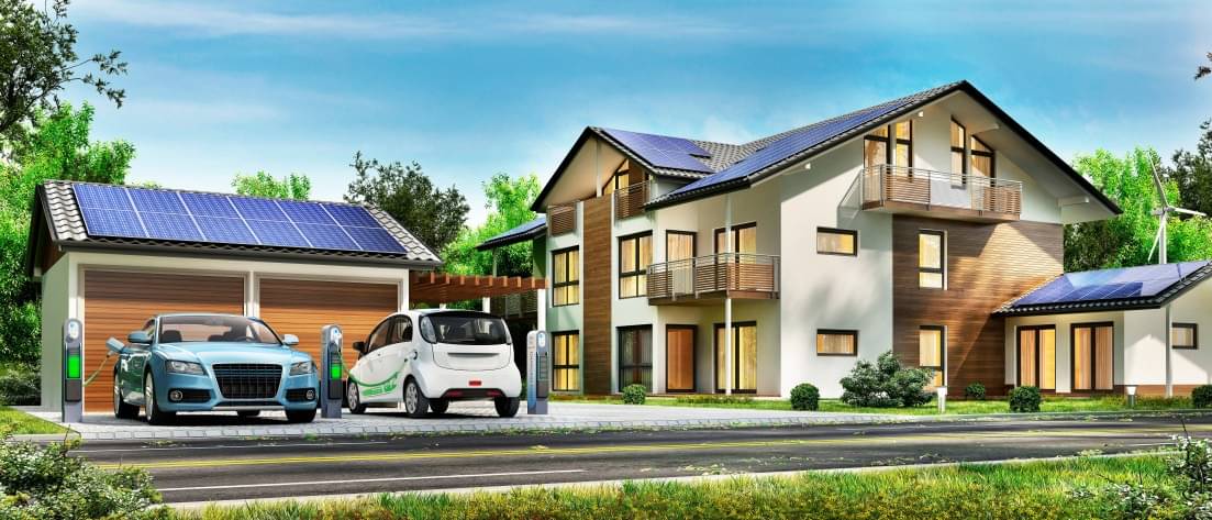 Modernes Haus mit Solaranlagen auf dem Dach und zwei elektrischen Ladestationen, an denen jeweils ein E-Auto geladen wird.