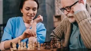 Krankenpflegern spielt Schach mit einem älteren Mann.