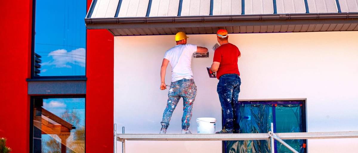 Zwei Männer streichen die Fassade eines Hauses - Fassade streichen