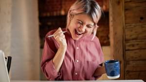 Junge Frau hält freudig die Faust in die Luft.