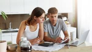 Zwei junge Menschen schauen sich konzentriert Unterlagen zu ihren Finanzen an.