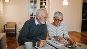 Eine Frau und ein Mann sitzen an einem Tisch und informieren sich über eine zusätzliche Altersvorsorge.