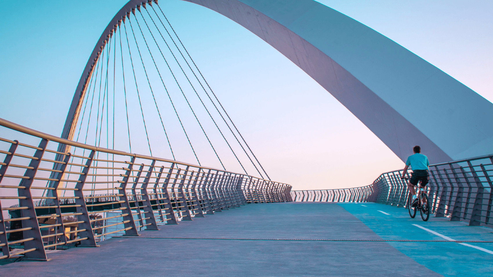 Fahrradfahrer fährt zur blauen Stunde auf architektonisch schöner Brücke