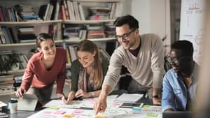 Junges Gründerteam plant gemeinsam an einem Tisch mit Notizen und Skizzen.