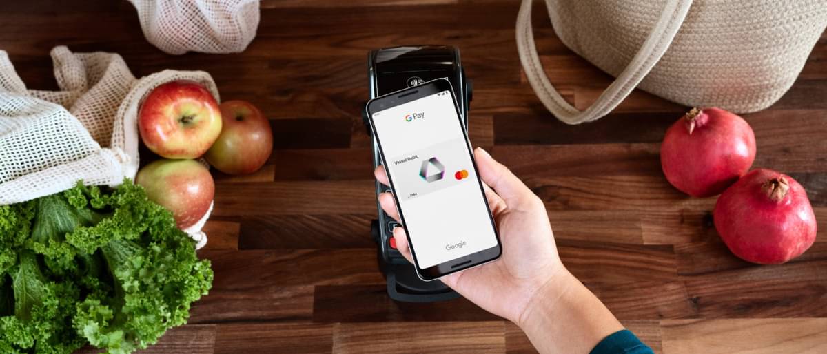 Ein Smartphone wird an ein Kartenlesegerät gehalten, um damit in einem Laden mit Google Pay für einen Einkauf zu zahlen.