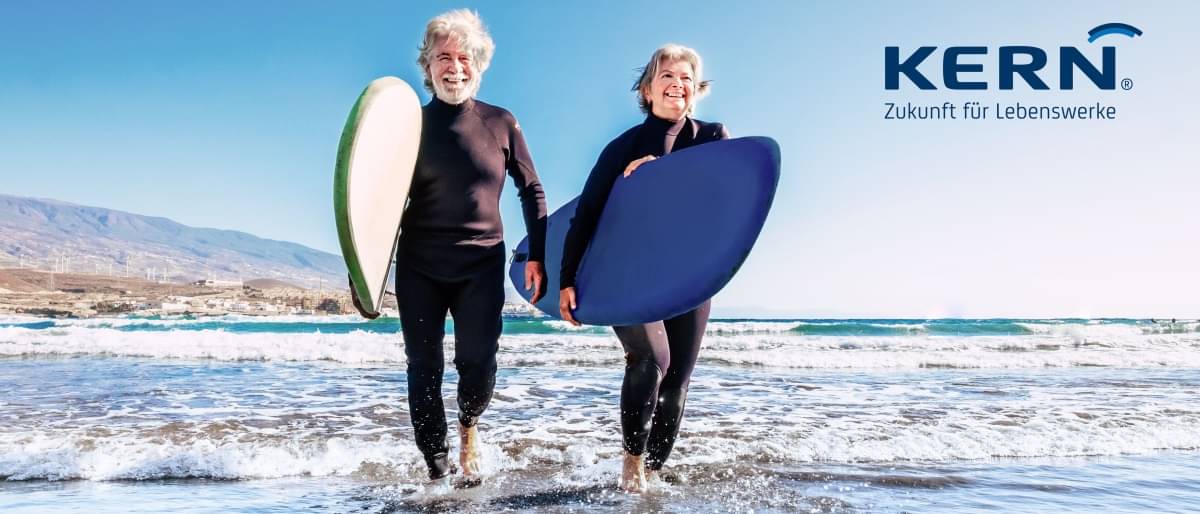 Ein älteres Paar mit Surfbrettern am Strand