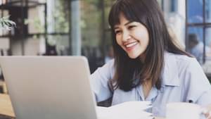 Junge Frau informiert sich am Laptop über Fonds-Sparpläne