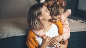 Ein kleines Mädchen schmiegt sich an die Schultern ihrer Mama.