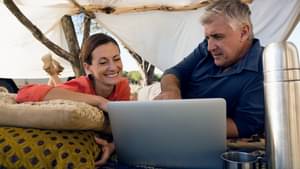 Ehepaar im Sommerurlaub schaut auf Laptop 