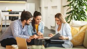 Ein junges Paar lässt sich von einer Frau zum Thema Bausparen beraten.