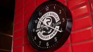 Fokus auf eine schwarze Wanduhr auf roten Fliesen im Style von Bestworscht