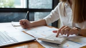 junge frau mit taschenrechner und laptop