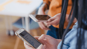 Zwei Personen, die jeweils ein Handy in der Hand haben und sich dazu gemeinsam austauschen 