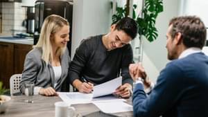 Zwei junge Menschen, ein Mann und eine Frau unterschreiben glücklich einen Vertrag