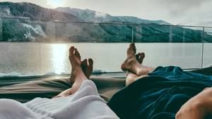 zwei Menschen, die an einem See liegen und den Sonnenuntergang genießen