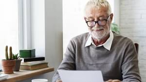 Älterer Mann hat seine Lesebrille auf und schaut auf ein Dokument zum Thema Rentenpunkte berechnen