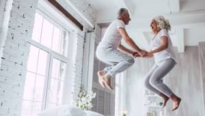 Senioren-Paar haben Spaß und springen zusammen auf ihrem Bett umher