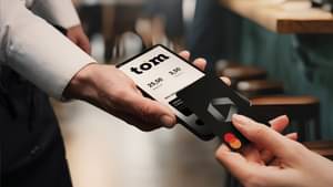 Ein Commerzbank-Karte wird an ein Handy mit Kartenzahlungsfunktion gehalten