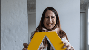 Christina Diem-Puello hält das Commerzbank-Logo vor  sichund lacht herzlich in die Kamera.