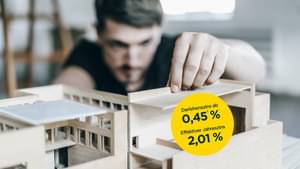 Mann im Hintergrund mit Architekturmodell im Vordergrund, an dem der Mann gerade arbeitet und sehr intensiv begutachtet.