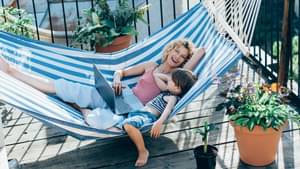Eine Frau liegt lachend mit ihrem Sohn auf einer Hängematte