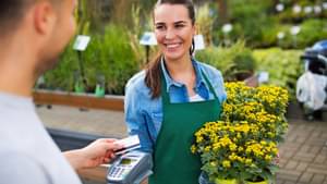 Mann im Gartencenter hält Angestellten seine Karte hin