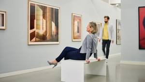 Das Foto im Fotografie Forum in Frankfurt zeigt Dr. Stephanie Kenedi sitzend auf einer Bank während sie die Ausstellung genießt.