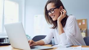 Junge Frau lächelt und arbeitet am Laptop im Homeoffice