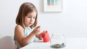 Kleines Mädchen, die eine Geldbörse in der Hand hält, schaut sich eine Münze genau an