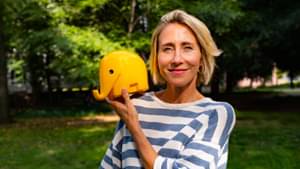 Julia Haussig - Spezialistin für Kinder- und Familienfinanzen. Sie lächelt in die Kamera und hält einen gelben "Drumbo"-Elefanten auf der Schulter.