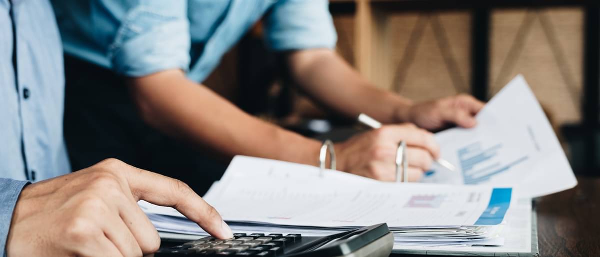 Tisch bedeckt mit Unterlagen und Taschenrechner - Rendite