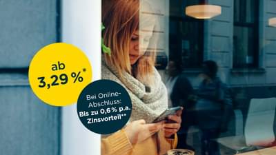 Junge Frau steht hinter bodentiefen Fenster mit Schal und gelbem Oberteil. Sie hält Handy in der Hand und tippt auf dem Bildschirm: Onlinekredit ab 3,29% p.a.* und zusätzlichen Zinsvorteil bei Online-Abschluss von bis zu 0,6% p.a.**