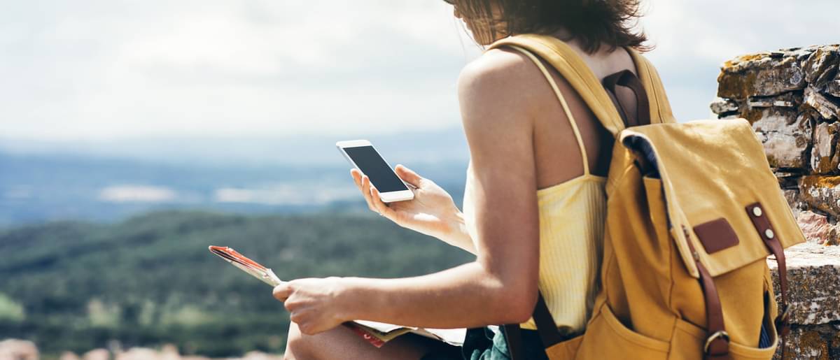 Frau sitzt auf Berg mit Handy